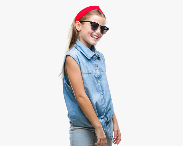 Young beautiful girl wearing sunglasses over isolated background looking away to side with smile on face, natural expression. Laughing confident.
