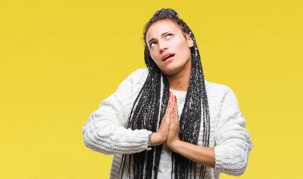 Young braided hair african american girl wearing sweater over isolated background begging and praying with hands together with hope expression on face very emotional and worried. Asking for forgiveness. Religion concept.