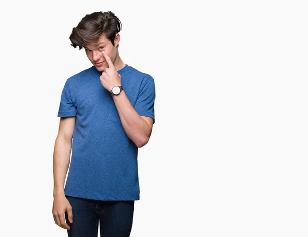 年轻的帅哥穿着蓝色的 T恤在孤立的背景指向眼睛看着你的手势 可疑的表情 — 图库照片