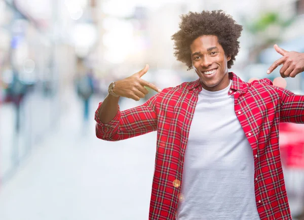 Afro american man over isolated background looking confident with smile on face, pointing oneself with fingers proud and happy.