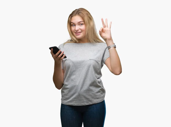 年轻的高加索妇女发送消息使用智能手机在孤立的背景做确定的标志与手指 优秀的符号 — 图库照片