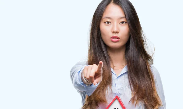 年轻的亚洲妇女真实的状态代理持有房子孤立的背景指向相机和你 正面和自信的手势从前面 — 图库照片