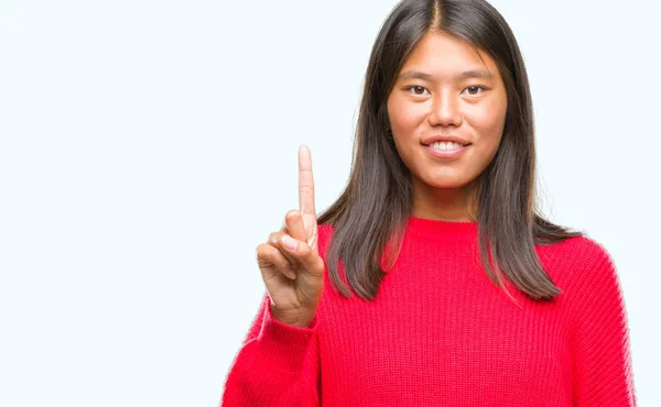 年轻的亚洲妇女穿着冬季毛衣在孤立的背景显示和指向与手指第一 而微笑着自信和快乐 — 图库照片