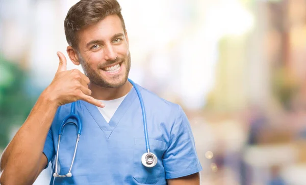 年轻英俊医生外科医生人在孤立的背景微笑做电话手势用手和手指像在电话交谈 沟通概念 — 图库照片