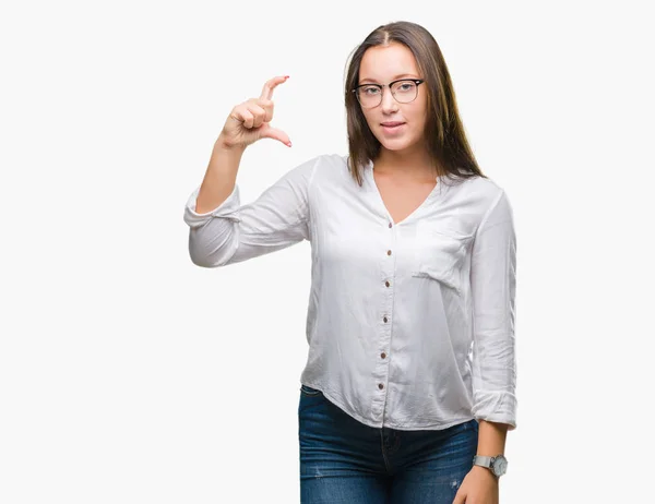 年轻的高加索美丽的女商人戴着眼镜在孤立的背景微笑和自信的手势与手做大小标志与手指 而看和相机 测量概念 — 图库照片