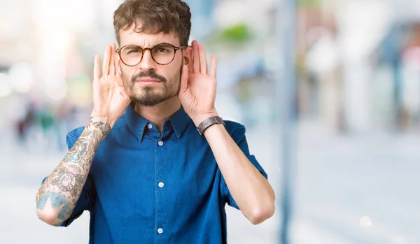 Joven Hombre Guapo Usando Anteojos Sobre Fondo Aislado Tratando Escuchar —  Fotos de Stock