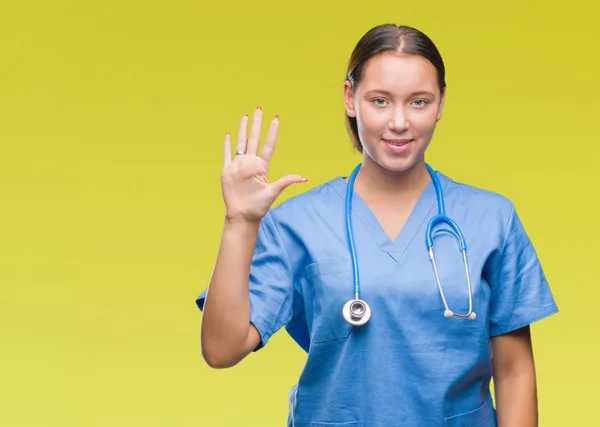 年轻的白种人医生妇女穿医疗制服在孤立的背景显示和指向与手指数字五同时微笑自信和快乐 — 图库照片