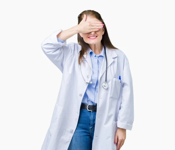 中年中高年医師女性は微笑し 笑う顔驚きの目を覆っている手で孤立した背景に医療のコートを着てします 視覚障害者の概念 — ストック写真