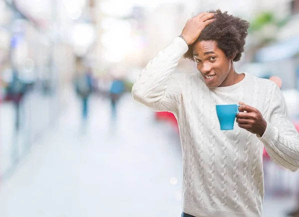 Afro american man drinking cup of coffee over isolated background stressed with hand on head, shocked with shame and surprise face, angry and frustrated. Fear and upset for mistake.