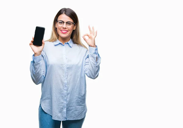 年轻美丽的女商人显示在孤立的背景上的智能手机空白屏幕做确定的标志与手指 优秀的符号 — 图库照片