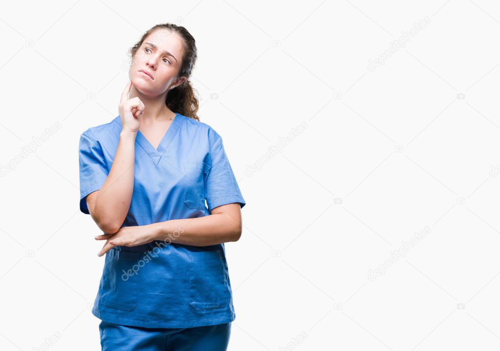 Young brunette doctor girl wearing nurse or surgeon uniform over isolated background with hand on chin thinking about question, pensive expression. Smiling with thoughtful face. Doubt concept.