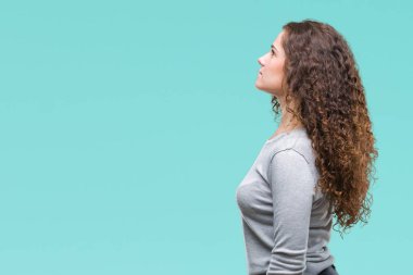 Güzel esmer kıvırcık saç üzerinde bir kazak giyen genç kız tarafına, seyir arka plan izole dinlenmek doğal yüz emin gülümseme ile pozuyla profili.