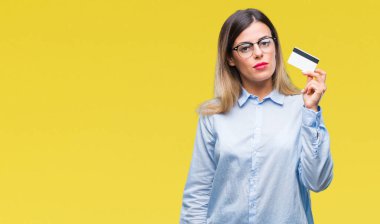 Acımak yüz ciddi düşünüyorum üstünde kendine güvenen bir ifade ile izole arka plan üzerinde kredi kartı tutan genç güzel iş kadın