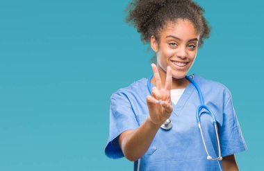 Genç afro Amerikalı doktor kadın parmaklarını zafer işareti yaparken gösterilen kamera seyir gülümseyen izole arka plan yüzünden. İki numaralı.