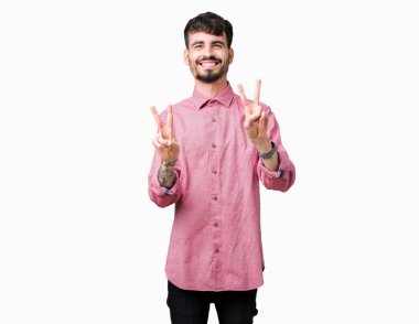 Zafer işareti yapıyor parmak gösterilen kamera seyir gülümseyen izole arka plan üzerinde pembe gömlek giymiş yakışıklı delikanlı. İki numaralı.