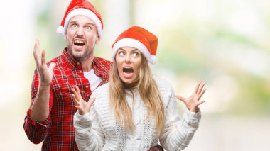 Üzerinde Noel şapka aşık genç çift arka plan çılgın ve kızgın bağırarak ve agresif ifade ve silah kaldırdı bağırmaya izole. Hayal kırıklığı kavramı.