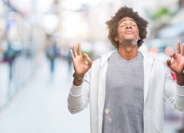Afro Amerikalı adam giyen kazak izole arka plan üzerinde dinlenmek ve gülümseyen gözlerle kapalı parmak jestle meditasyon yapıyor. Yoga kavramı.
