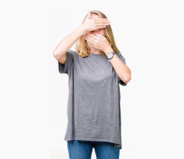 İzole arka plan kaplaması gözler ve ağız el ile üzerinden büyük boy rahat t-shirt giyen güzel ve genç birbayan şaşırttı ve şok. Duygu gizleme