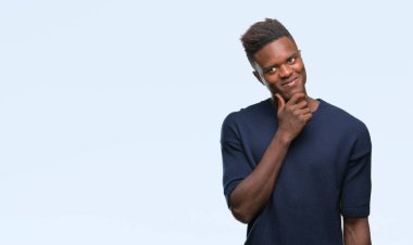 Afrikalı-Amerikalı genç çene düşünme hakkında soru, dalgın ifade üzerine el ile izole arka plan üzerinde. Düşünceli yüzüyle gülümsüyor. Şüphe kavramı.
