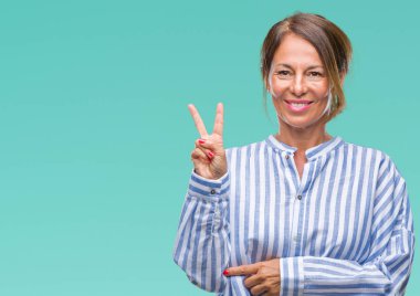 Orta yaş İspanyol kadın kıdemli mutlu yüz zafer işareti yaparken kameraya göz kırpıyor ile gülümseyen izole arka plan üzerinde. İki numaralı.