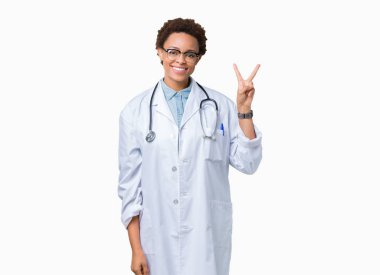 Mutlu yüz zafer işareti yaparken kameraya göz kırpıyor ile gülümseyen izole arka plan üzerinde tıbbi ceket giyen genç Afro-Amerikan doktor kadın. İki numaralı.