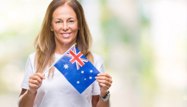 Avustralya bayrağı izole arka plan üzerinde duran ve diş gösterilen kendine güvenen bir gülümsemeyle gülümseyerek mutlu bir yüz tutan orta yaş İspanyol kadın