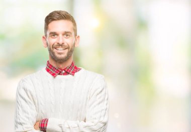 Mutlu yüz ile gülümseyerek kameraya seyir silah geçti arka plan üzerinde kış kazak giyen genç yakışıklı adam izole. Olumlu bir kişi.