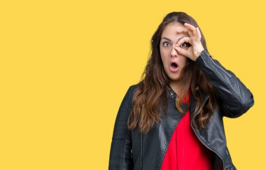 Artı boyutu genç kadın güzel Tamam jest yapıyor izole arka plan üzerinde moda deri ceket ile sürpriz yüz, göz parmaklarının arasından seyir şok. İmansız ifade.