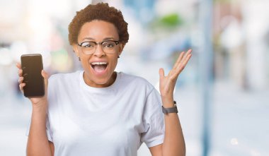 Smartphone ekran üzerinde gösterilen genç Afro-Amerikan kadın büyük gülümseme ile çığlık zaferini kutluyor ve ellerini kaldırdı arka plan çok mutlu ve heyecanlı, kazanan ifade izole