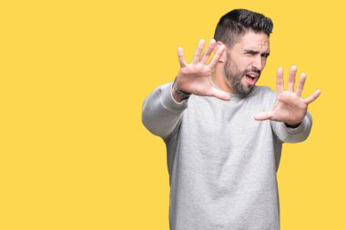 Üzerinde sweatshirt giyen genç yakışıklı adam arka plan korkuyor ve korku ifade dur hareketi el ile ile dehşete şokta bağırarak izole. Panik kavramı.