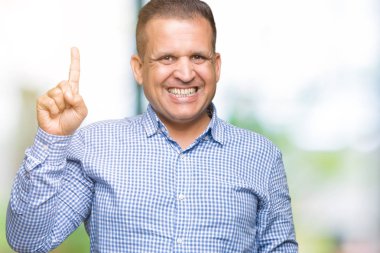 Orta yaş Arap iş adamı ve parmak gülümseyen süre bir numara ile kendinden emin ve mutlu yukarıyı gösteren izole arka plan üzerinde.