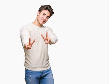 Arka planda kalan yakışıklı genç adam kameraya bakıp zafer işareti yaparken gülümsüyor. İki numara..