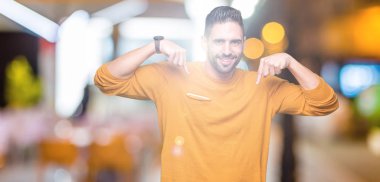 Yüzünde gülümseme ile kendinden emin görünüyorsun, kendini gururlu ve mutlu parmakları ile işaret izole arka plan üzerinde genç yakışıklı adam.