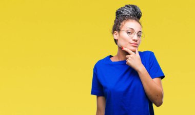 Genç saç Afro-Amerikan Kız emin çapraz kollar ve çeneme kaldırdı el ile gülümseme ile kameraya bakarak izole arka plan üzerinde gözlük takan örgülü. Pozitif düşünce.