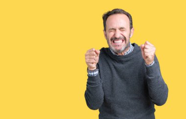 Zafer kutluyor gülümseyen yakışıklı orta komuta sizde izole arka plan üzerinde bir kazak giyen heyecanlı yaş silah ile başarı için kaldırdı. Kazanan kavramı.