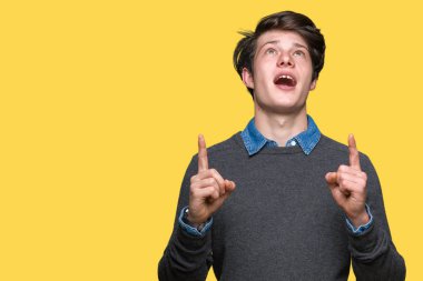 Genç yakışıklı zarif adam izole arka plan üzerinden hayran ve yukarıya bakıyor ve parmakları ile işaret ve silah kaldırdı sürpriz.