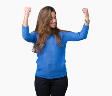 Kol kasları gururlu gülümseyen gösterilen izole arka plan üzerinde mavi kazak giyen genç güzel esmer kadın. Fitness kavramı.