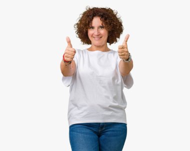 Hareketi el ile mutlu yaşasın yapıyor izole arka plan üzerinde beyaz t-shirt giyen güzel orta ager kadın kıdemli. Başarı gösteren kameraya bakarak ifade onaylama.