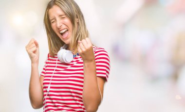 Üzerinde kulaklık giyen genç güzel kadın dinleme Müzik arka plan çok mutlu ve heyecanlı gülümseyen ve başarı için çığlık kaldırdı, silah ile kazanan jest yapıyor izole. Kutlama kavramı.