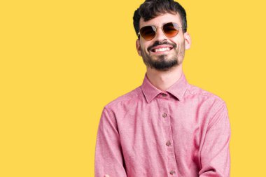 Yakışıklı delikanlı üzerinde güneş gözlüğü takıyor mutlu yüz ile gülümseyerek kameraya seyir silah geçti arka plan izole. Olumlu bir kişi.