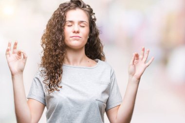 Güzel genç esmer kıvırcık saçlı kız rahat giyiyor bak izole arka plan üzerinde dinlenmek ve gülümseyen gözlerle parmak ile meditasyon jest yapıyor kapalı. Yoga kavramı.