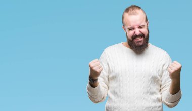 Üzerinde kış kazak giyen genç beyaz hipster adam arka plan çok mutlu ve heyecanlı kaldırdı, silah ile kazanan jest yapıyor gülümseyen ve başarı için çığlık izole. Kutlama kavramı.