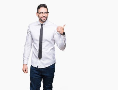 Seyir ve başparmak yanında yukarıyı mutlu yüz ile gülümseyen izole arka plan üzerinde gözlük takan genç yakışıklı iş adamı.