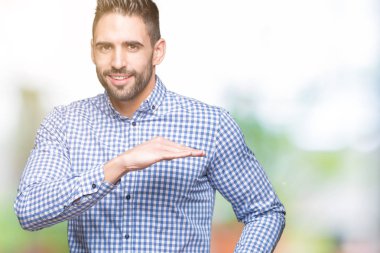 Yakışıklı delikanlı ile büyük ve büyük boy işaret, ölçü birimi sembol gösteren el eller izole arka plan üzerinde. Kameraya bakarak gülümsüyordu. Ölçüm kavramı.