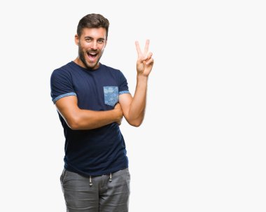 Mutlu yüz zafer işareti yaparken kameraya göz kırpıyor ile gülümseyen izole arka plan üzerinde genç yakışıklı adam. İki numaralı.