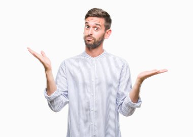 İzole arka plan clueless ve şaşkın bir ifadeyle kollar ve eller kaldırdı genç yakışıklı adam. Şüphe kavramı.