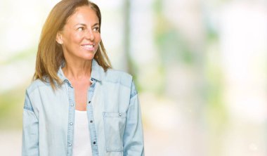 Orta yaş yetişkin kadın üzerinde rahat kot gömlek giymiş arka plan uzak tarafına gülümseme ile yüzünde, doğal ifade arıyorum izole. Kendine güvenen gülüyor.