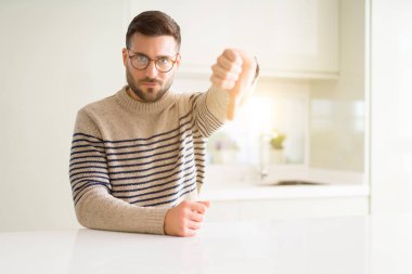 Genç yakışıklı adam gözlük evde kızgın suratla, sevmediğim başparmak aşağı, ret kavramı ile gösterilen işareti negatif.