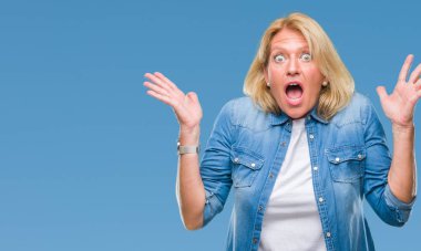 Orta yaş sarışın kadın deli kutluyor arka plan izole ve başarı için kaldırdı kollarını açarak hayrete ve heyecanlı çığlık gözleri açık. Kazanan kavramı