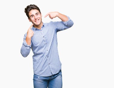 Genç yakışıklı iş adamı kendine güvenen gösterilen ve işaret parmakları diş ve ağız ile gülümseyen izole arka plan üzerinde. Sağlık kavramı.